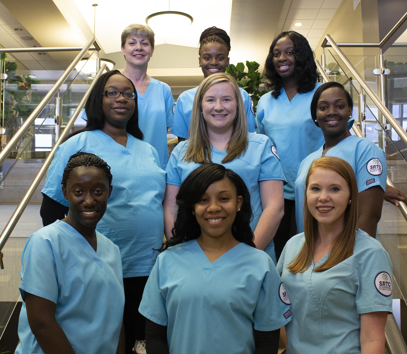 group of medical assisting students standing on stairs in scrubs